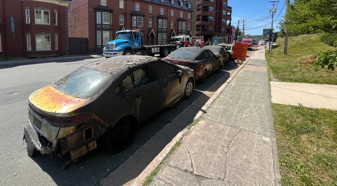 Three burnt black cars in line on road