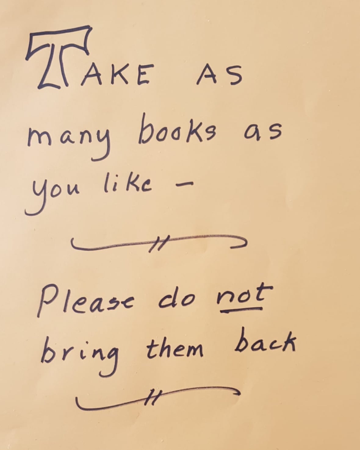 A handwritten sign saying "Take as many books as you want. Please do not bring them back."