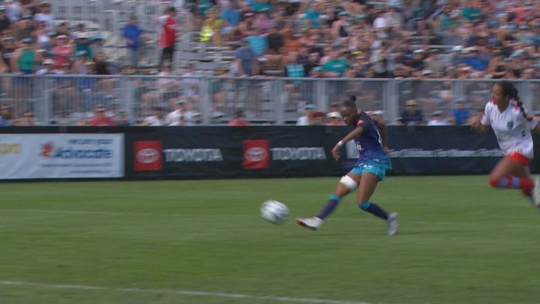 A female soccer player kicks the ball with her right foot during a match.