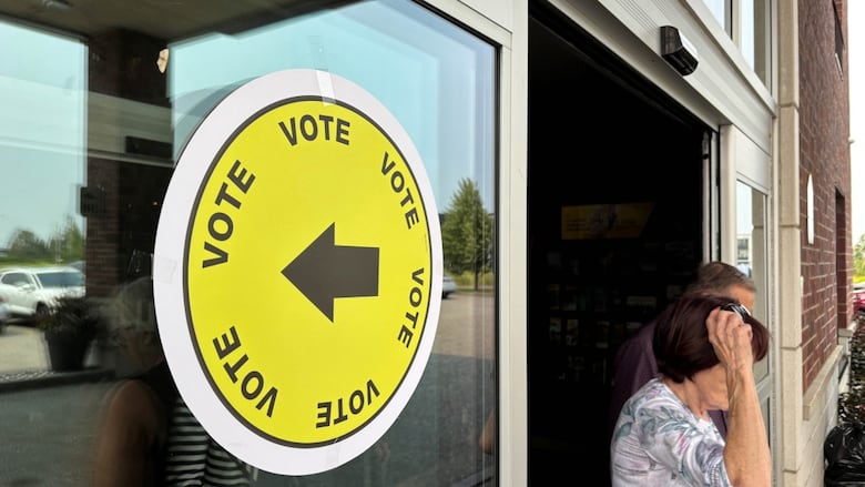Two people are seen exiting a building where voting is taking place.