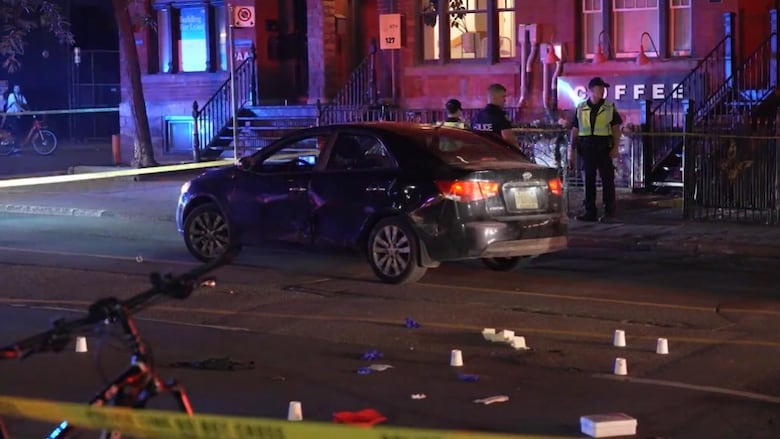Photo of a car behind police tape at nighttime in downtown Toronto
