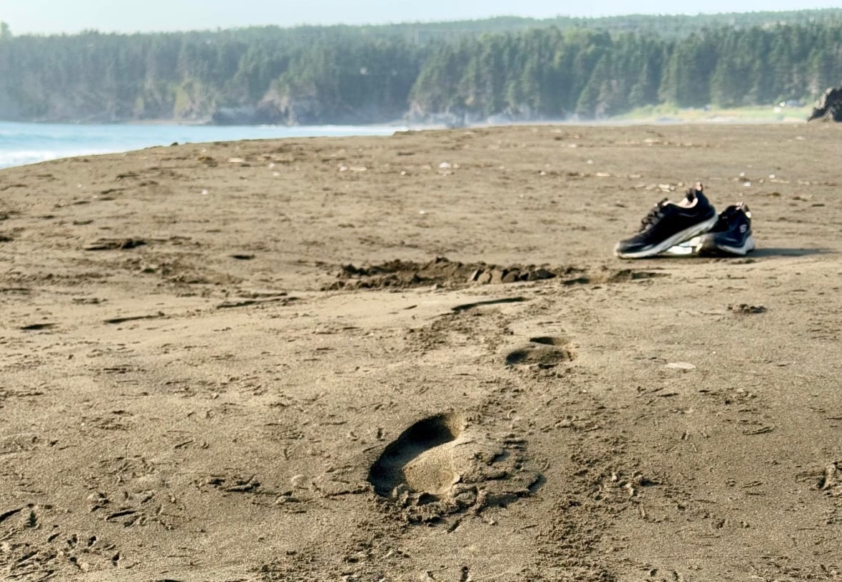 Foot print and sneakers in sand