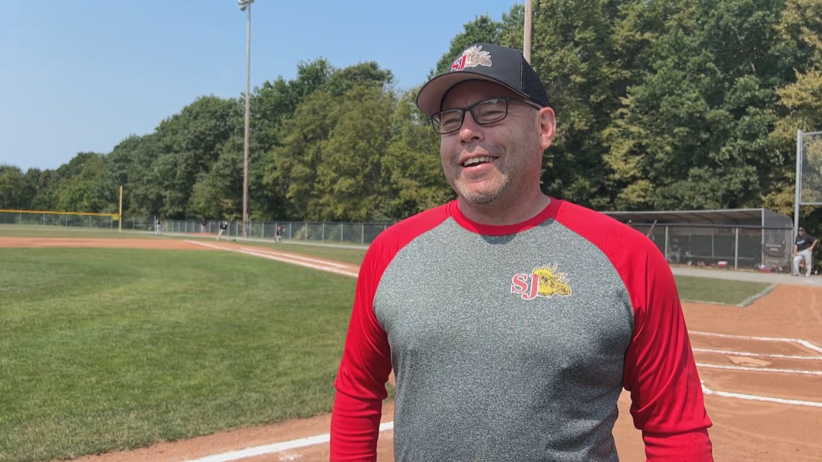 A man in a black baseball cap and a red and gray shirt.