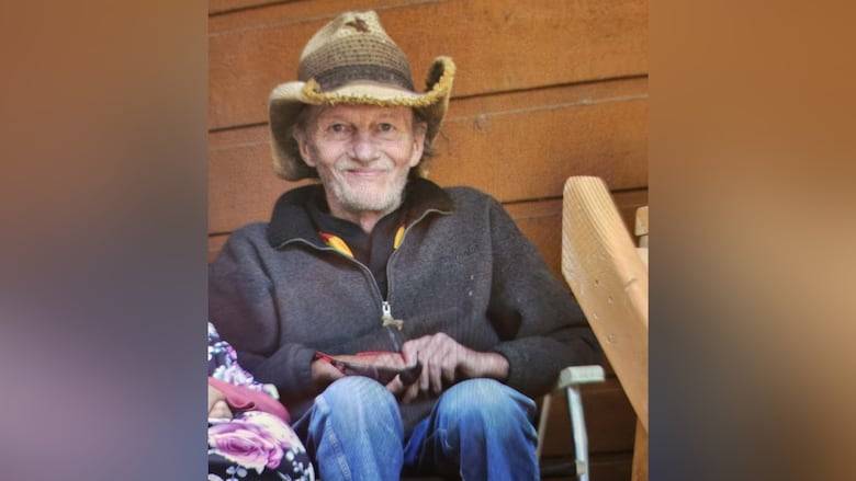 A man is sitting on a chair with a cowboy hat and jacket.