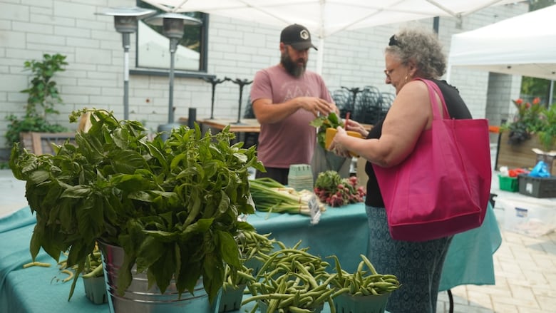 A man hands a woman some produce at a farmers' market in Ottawa.