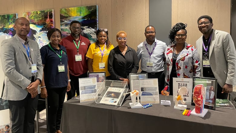 A group of members pose in front of the table that hold the journal in a display box