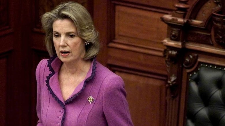 A woman delivers a speech behind a podium with two microphones
