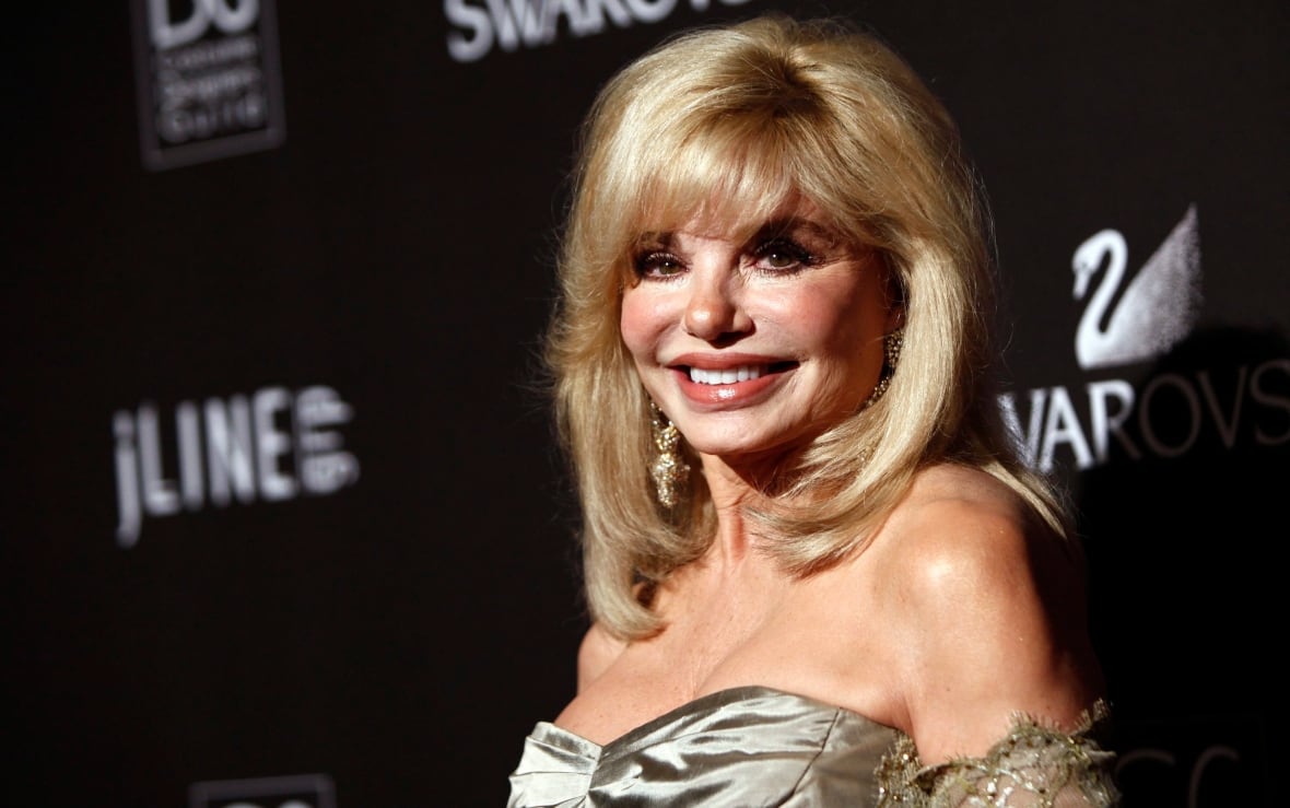 A blonde woman wearing a capital garment that affects a photograph