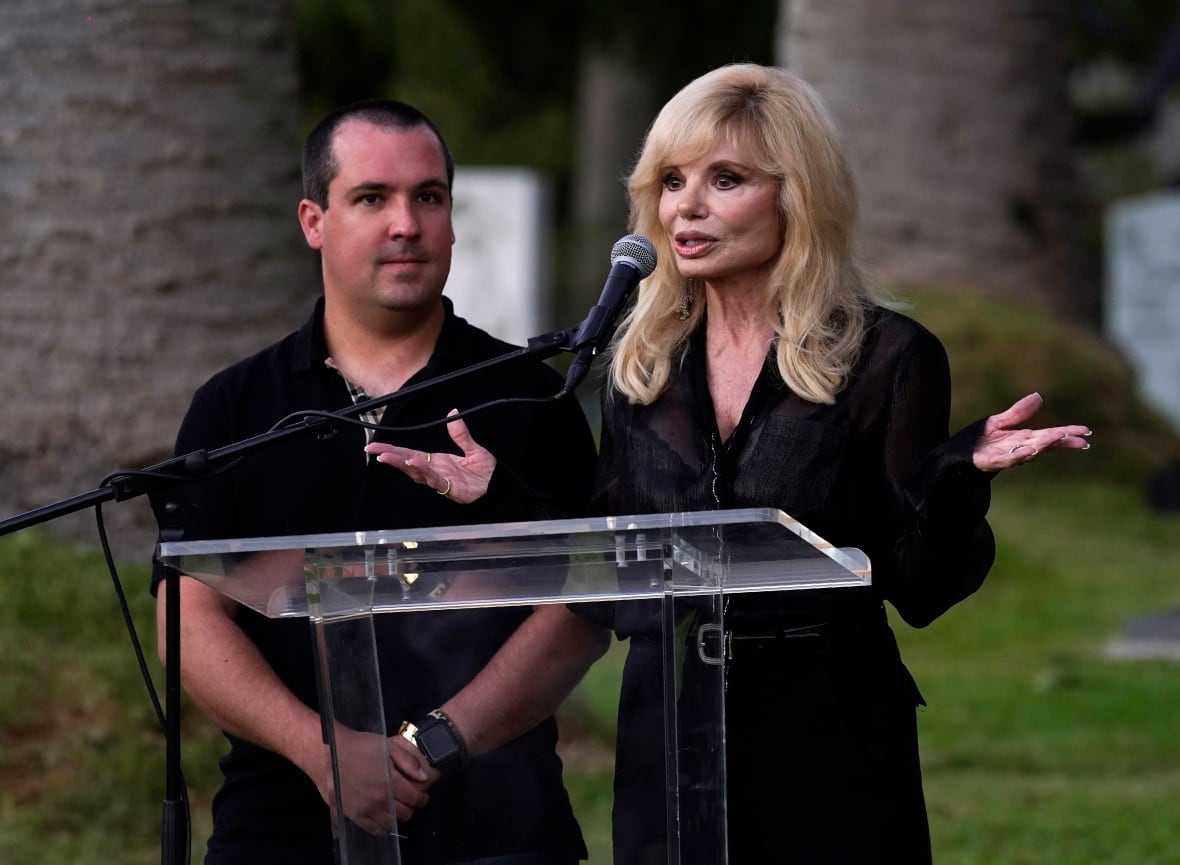 The woman holding black talking to a speech behind the platinum. A little one who holdeth in black behind him on his right hand.