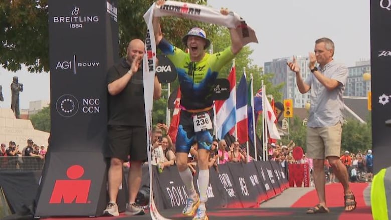 A man cheers as he crosses a finish line.