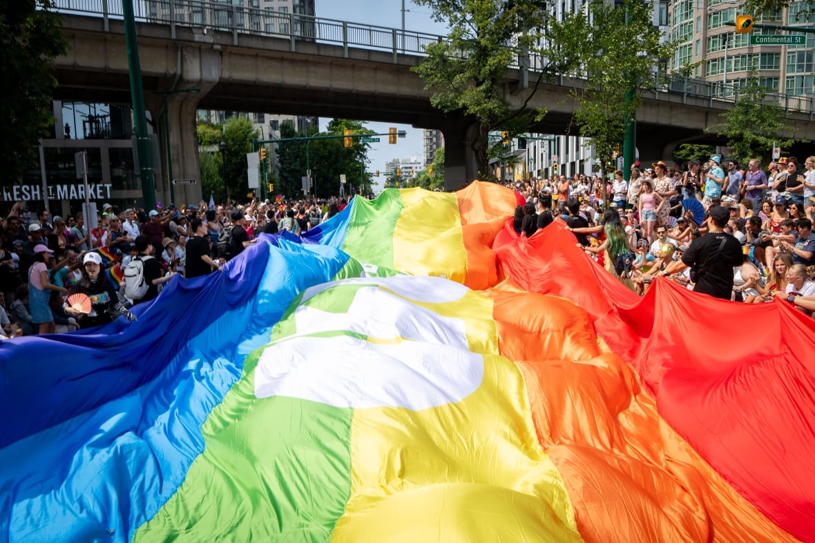 People watch as a giant pride flag passes during the parade. Organizers say an estimated 200,00 to 300,000 people participated. 