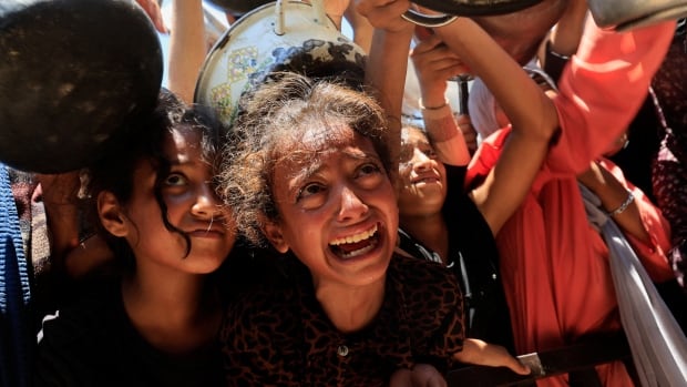 Young girls look up to receive food from a soup kitchen.