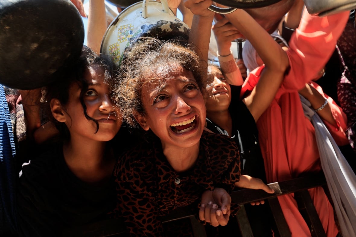 Young girls look up to receive food from a soup kitchen.