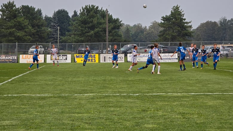 Soccer players in blue and while jerseys play a game on an outdoor field.