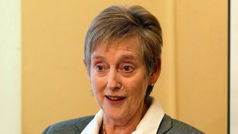 A woman with short greying hair is shown from the shoulders up. 