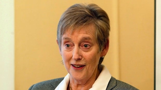 A woman with short greying hair is shown from the shoulders up. 