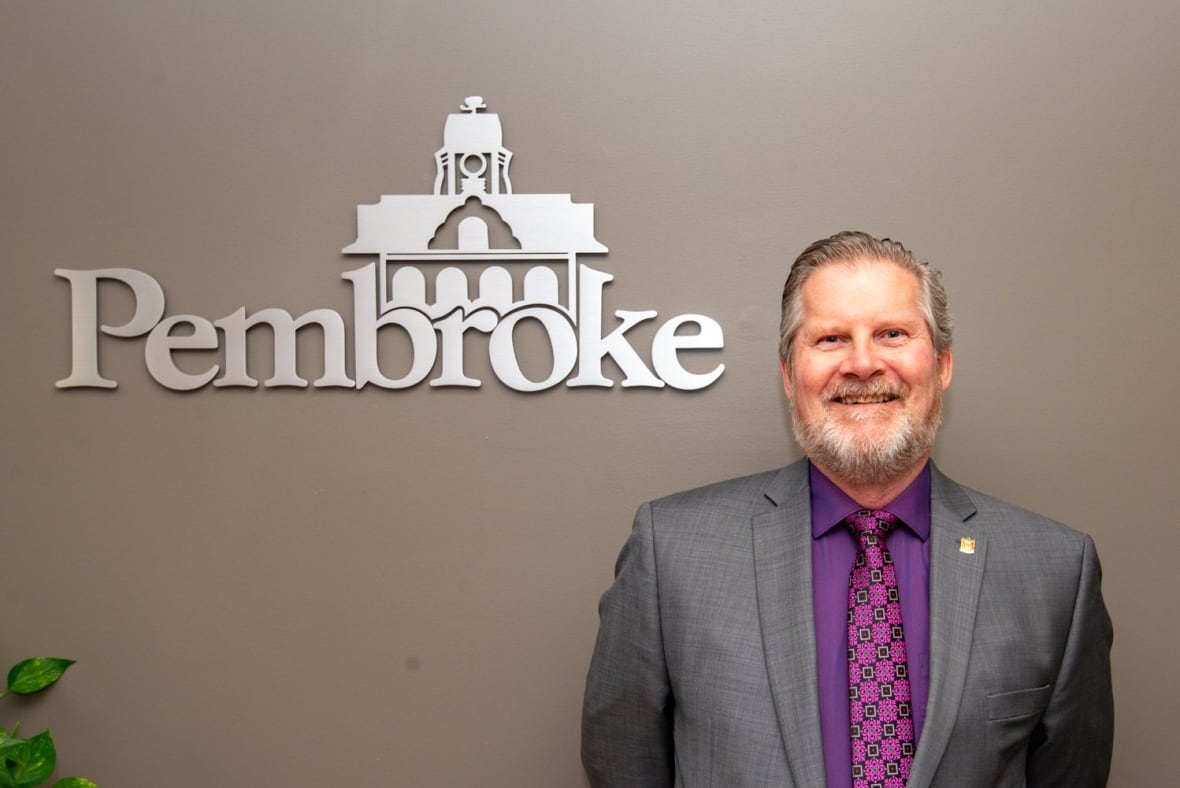 Pembroke's Deputy Mayor Brian Abdallah stands screen-right, smiling at the camera.