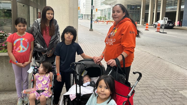 A woman stands with a group of children outside a hotel.