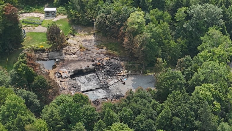 Overview photo of a burned down house and yellow police tape around the property. 