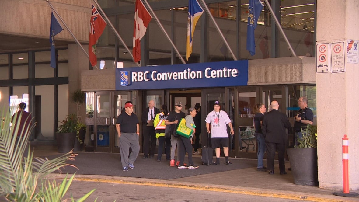 A group of people are outside a door with flags on the top.