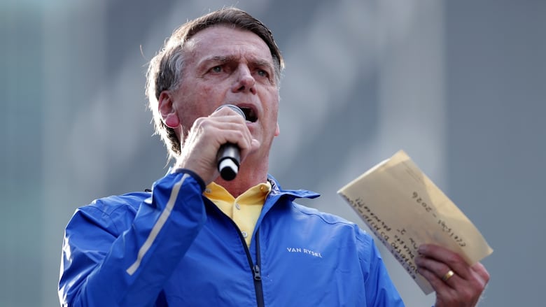A person speaks while holding a microphone and a piece of paper.