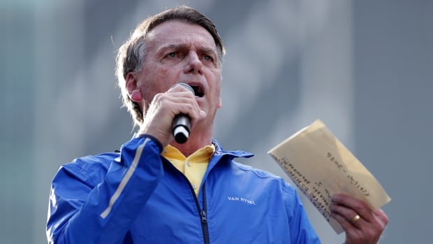 A person speaks while holding a microphone and a piece of paper.