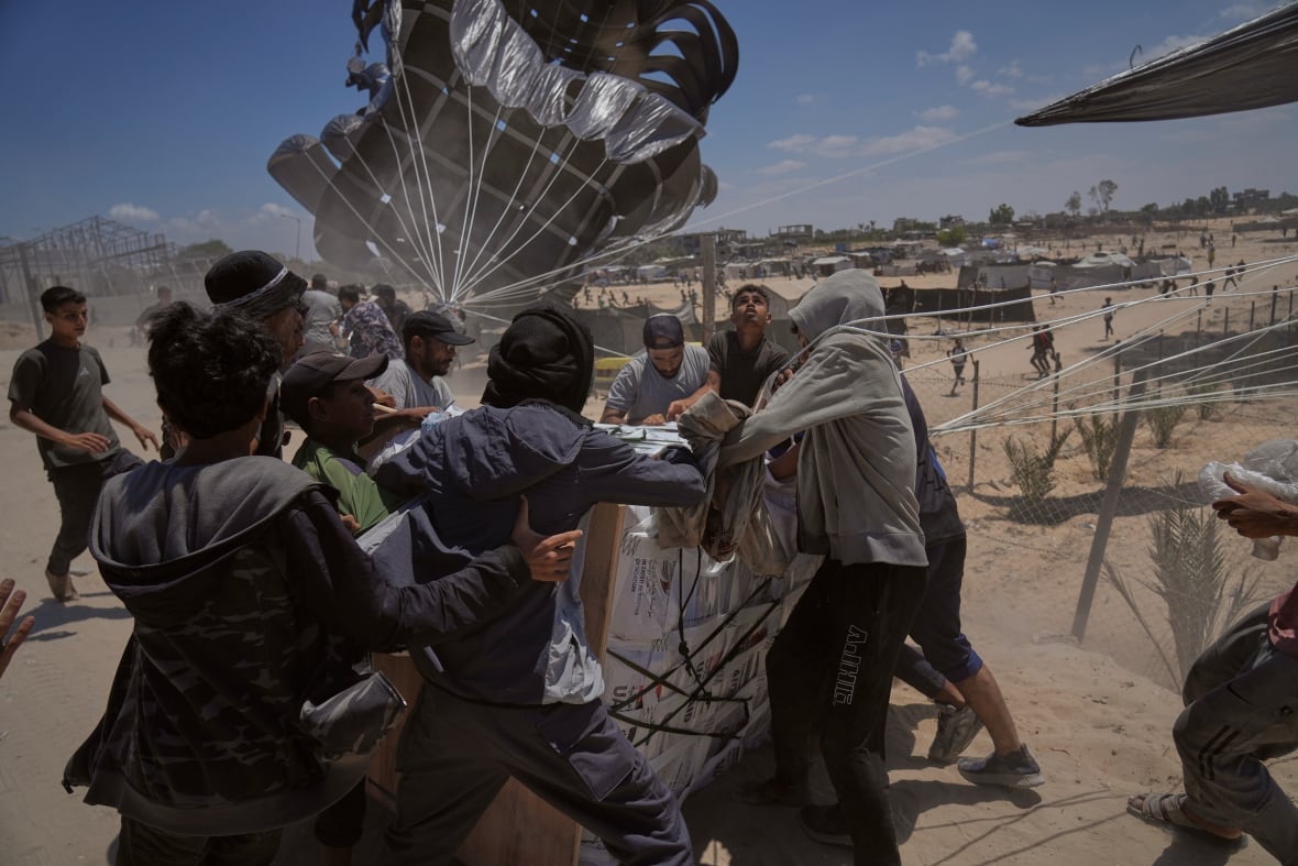Los palestinos corren para recolectar ayuda humanitaria en el avión a través del paracaídas.