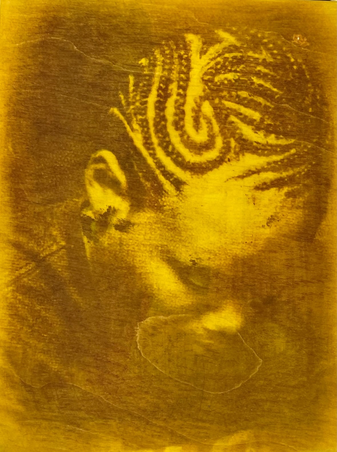 A grainy print on a yellow panel shows the closeup of a person's head with intricately braided hair.