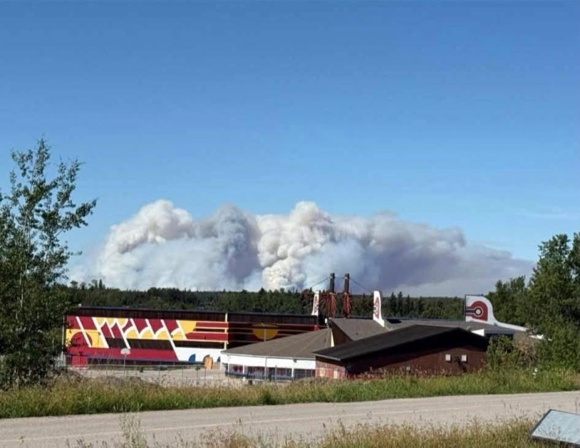 A large plume of wildfire smoke hangs in the air over a community.