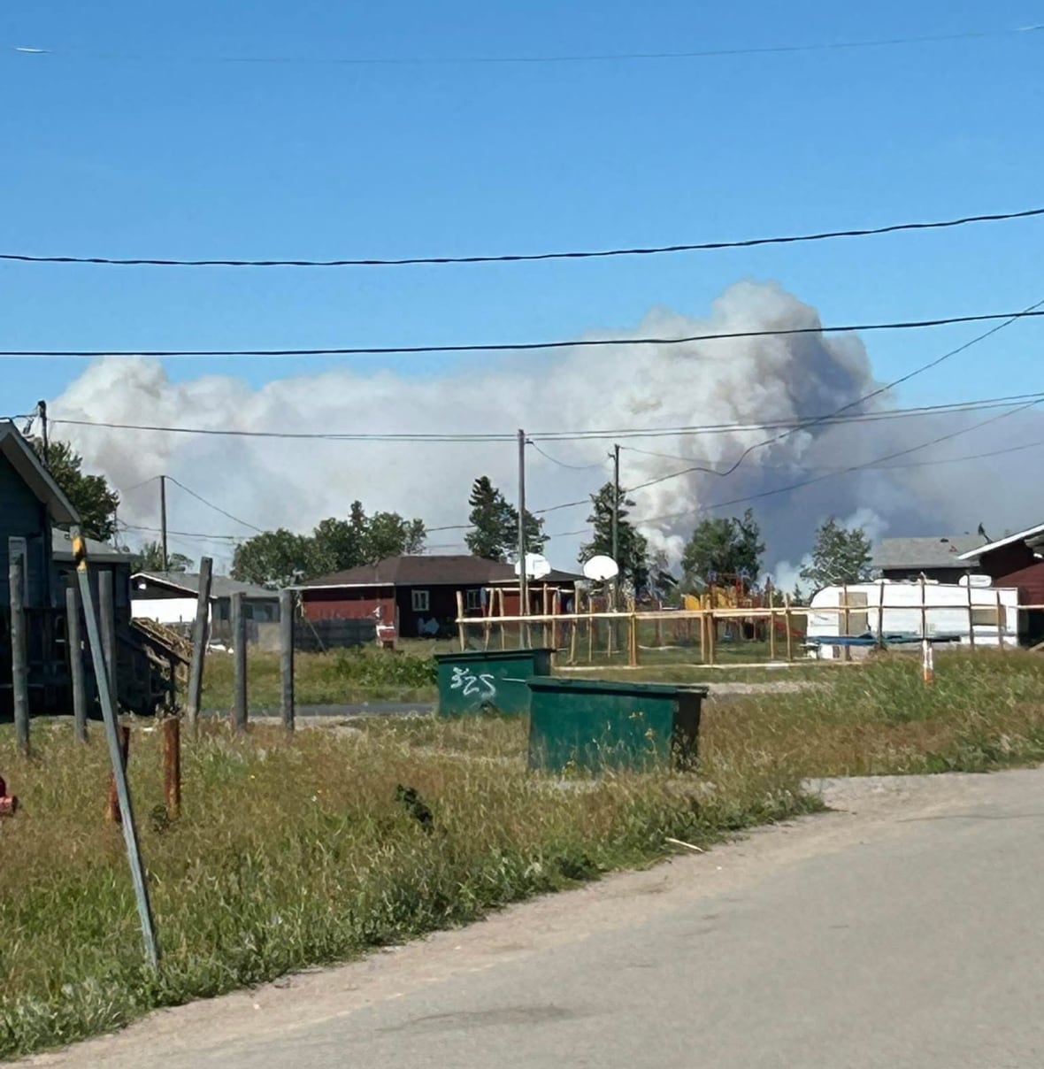 A large plume of wildfire smoke hangs in the air over a community.