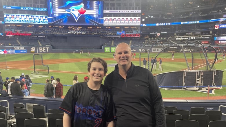 Man and teen stand in front of Blue Jays arena