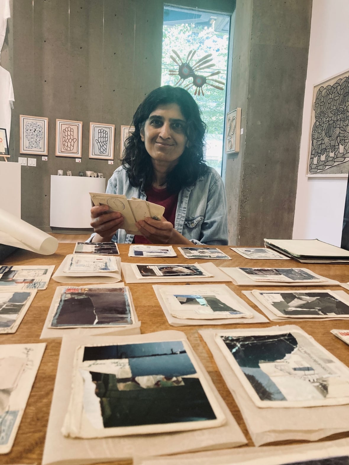 Seema Shah sits in front of her shipping tag collages.