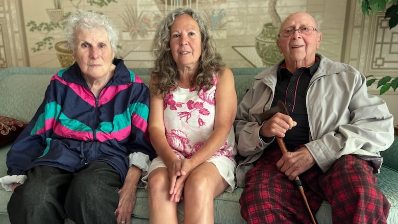 Three people sitting on a couch.