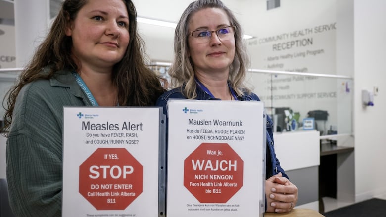 Tina Meggison, right, and Nely Penner, community health reps for the Low German Mennonite community in southern Alberta, are seen with signs in English and Low German at the Taber Community Health Clinic in Taber, Alta., Monday, July 28, 2025.