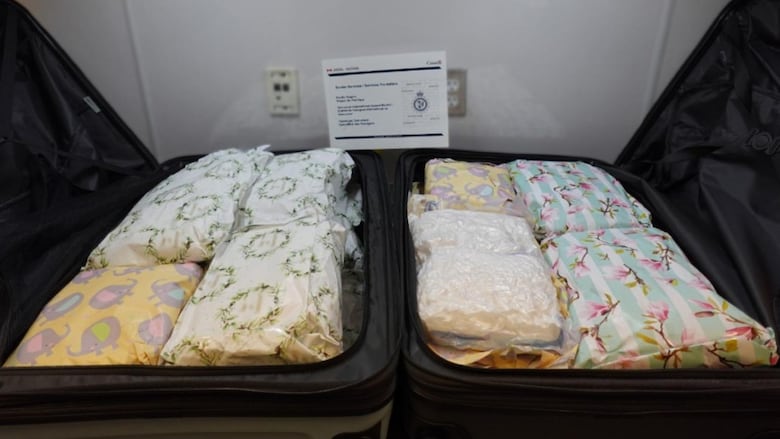 Packages of methamphetamine are wrapped in floral and baby-themed gift wrap and tucked into two black suitcases.
