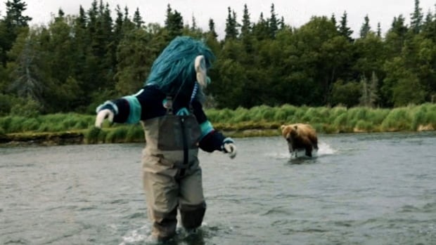 A bear charges towards a mascot in a river.