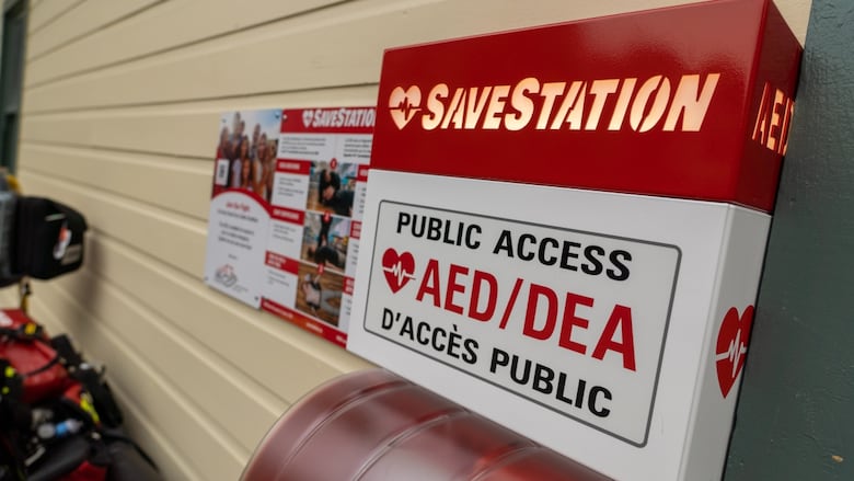 A public AED station is pictured on a wall. It says public access AED in bold letters.  