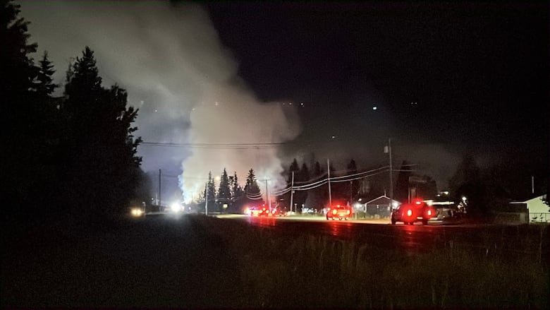 A dark highway with police cars and smoke.
