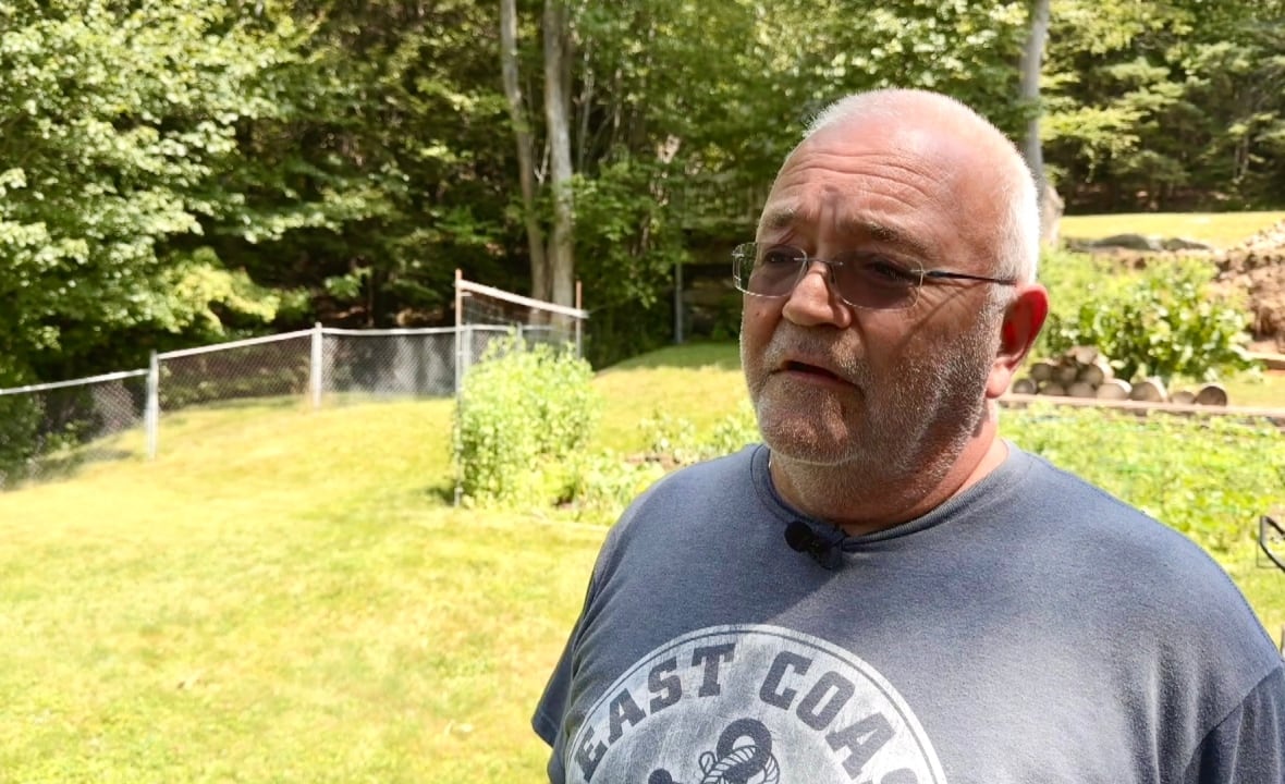A man standing in a yard wearing glasses and a t shirt.