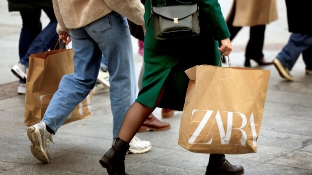 Women carry brown paper bags with "Zara" written on the sides in white.