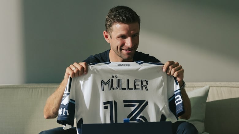 Man holds up a jersey.