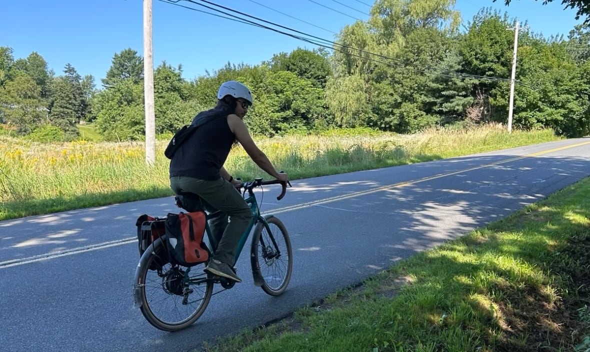 A man rides a bicycle along the edge of a road.