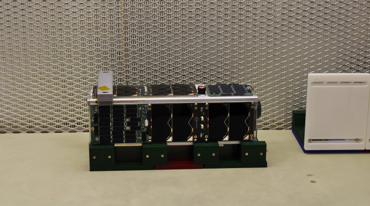 特写镜头：一个长长的黑色矩形，被称为立方体卫星 (CubeSat)。