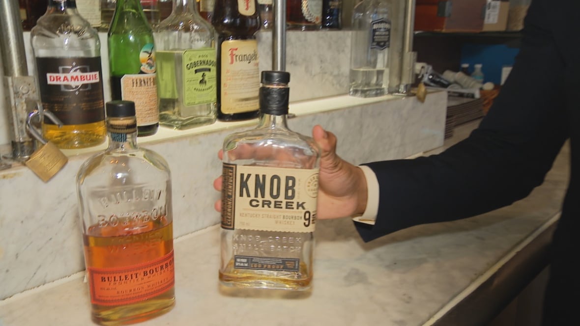 A marble bar has two bottles of sitting whiskey.