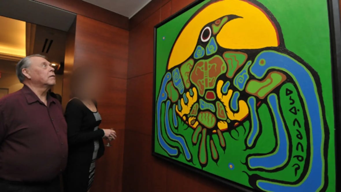 A man with grey hair looks at a large, green woodlands-style painting.
