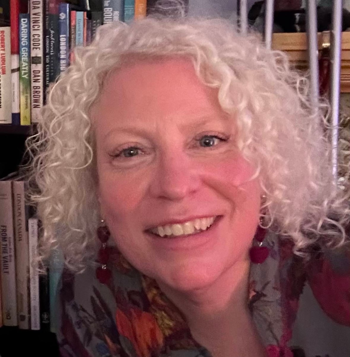 woman stands by bookshelf