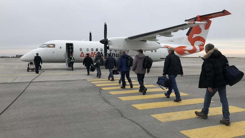 Passengers walking on a tarmac toward an Air Inuit plane.