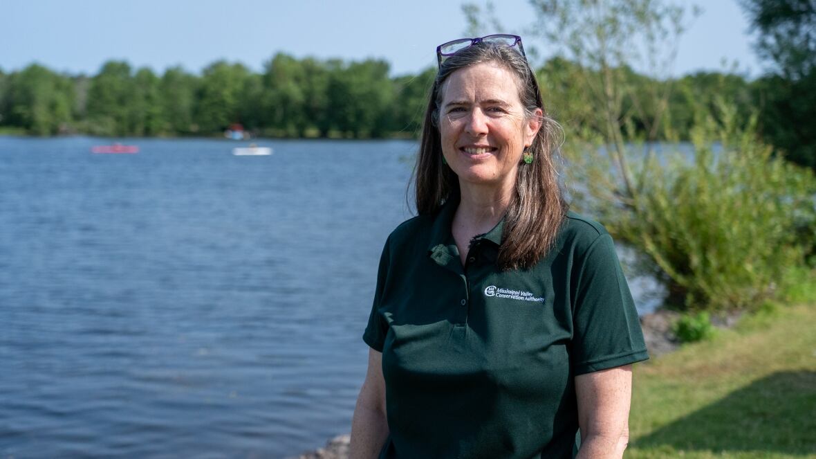 A conservation manager smiles near a body of water.