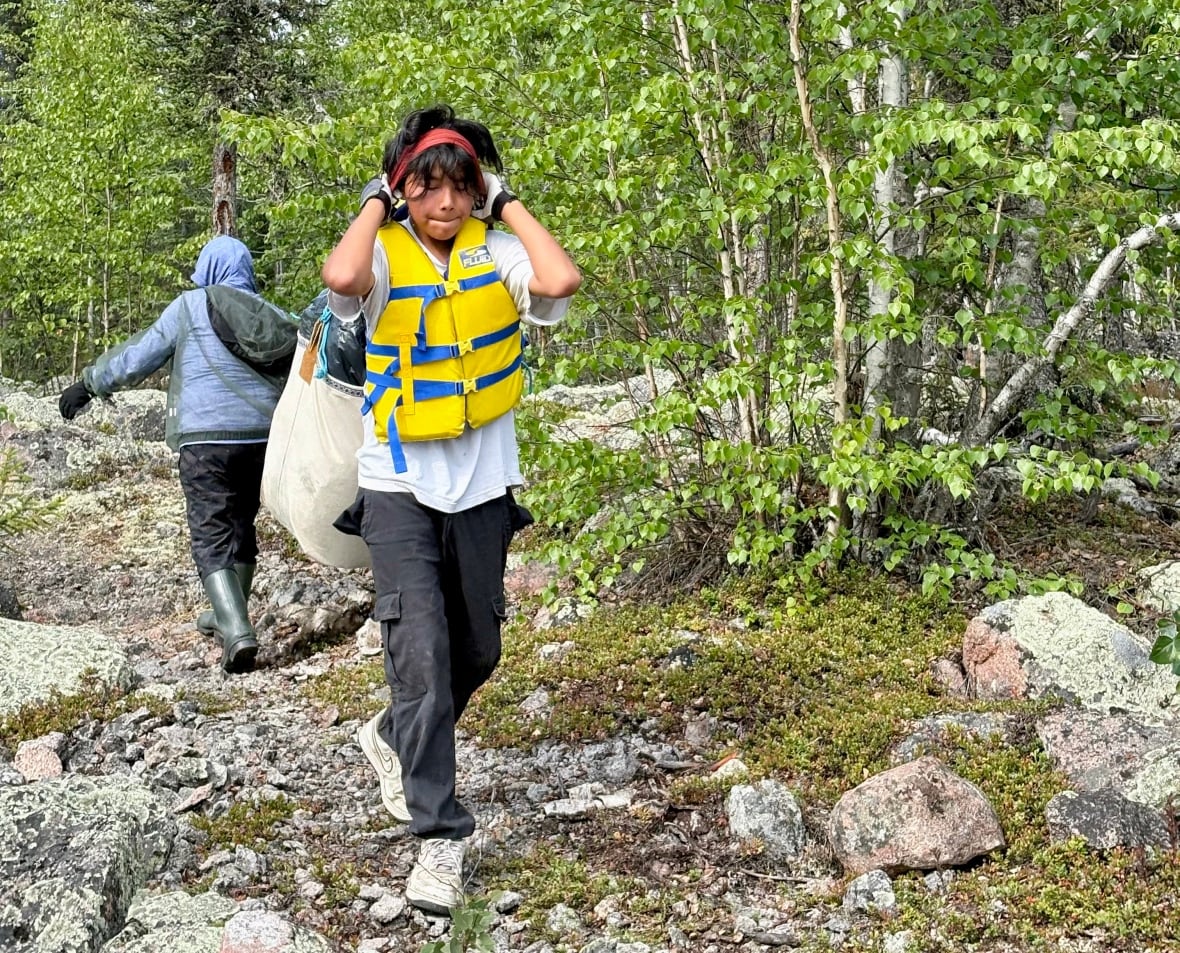 A young person carries a pack on a trail.