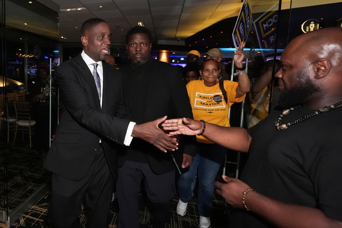 Solomon, wearing a suit, extends his hand to another man.